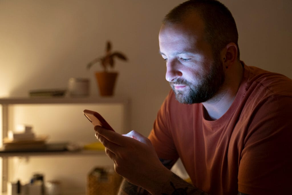 Mulher ansiosa digitando rapidamente no celular em um ambiente colorido, representando o reflexo emocional no WhatsApp