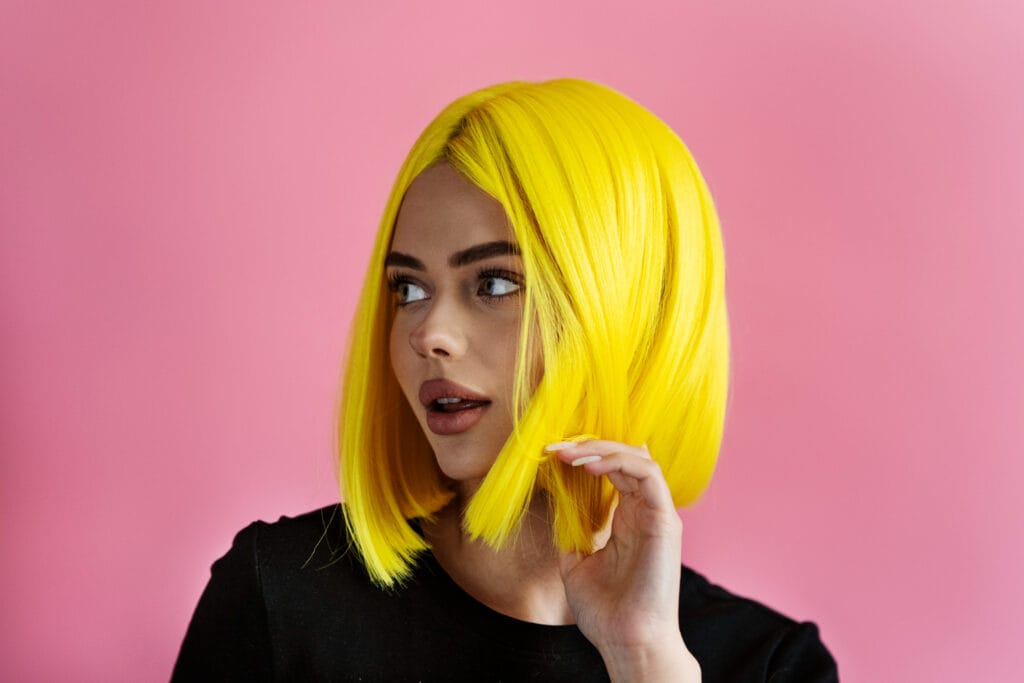 Mulher tocando os cabelos com expressão cansada, hábitos com o cabelo