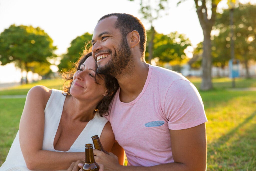 Casal maduro sorrindo e se abraçando em um parque, simbolizando uma vida a dois construída com amor duradouro e cumplicidade