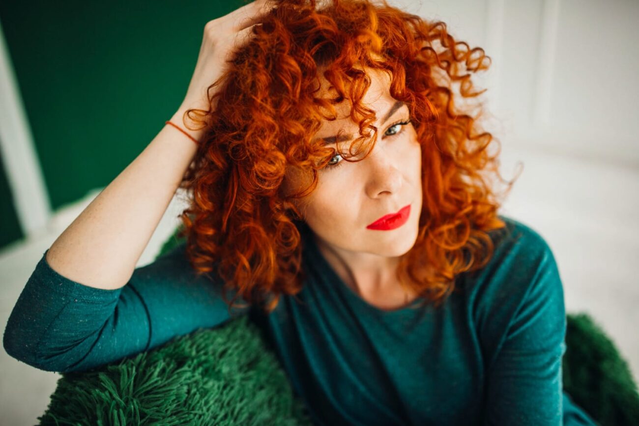 Mulher olhando no espelho com expressão pensativa, refletindo seu medo de mudar o corte de cabelo e suas consequências.