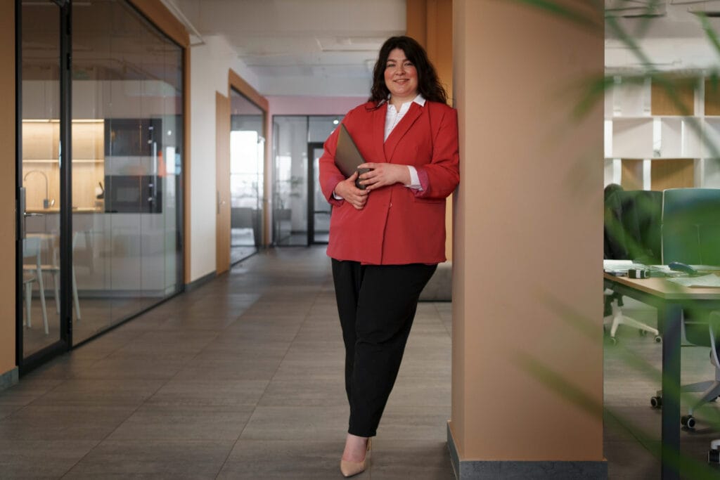 Mulher em pé, com ombros para trás, demonstrando a conexão entre postura e poder em um ambiente de trabalho