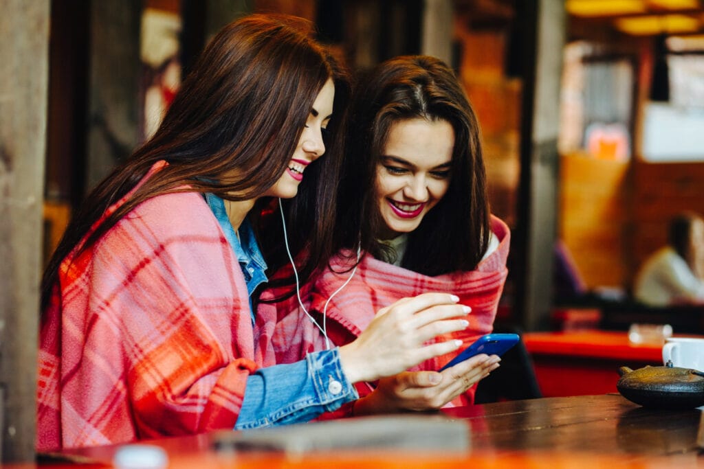 Adolescente sorrindo para a tela do computador, engajado em suas amizades virtuais com fones de ouvido