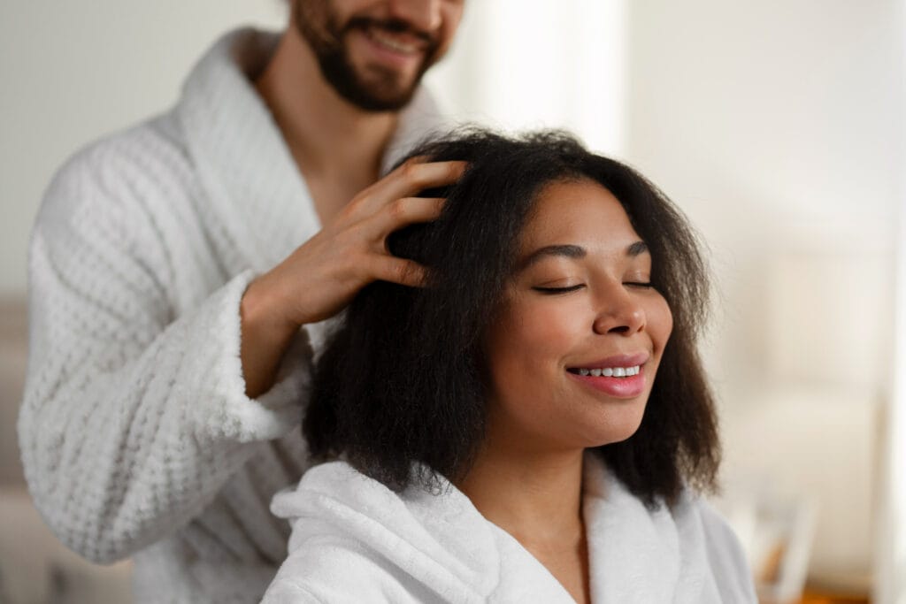 Mulher olhando para o espelho, preocupada com a perda de cabelo, com as mãos nos fios.